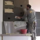 Patrizio Tapparelli impegnato nell'intonacatura della parte in muratura di una stufa ad olle.